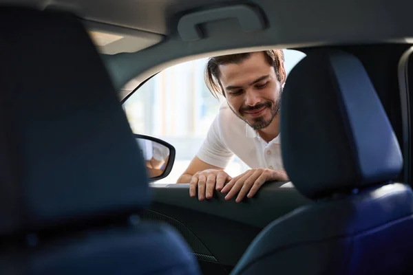 Uśmiechnięty Młody Klient Salonu Samochodowego Patrząc Wewnątrz Samochodu Osobowego Przez — Zdjęcie stockowe