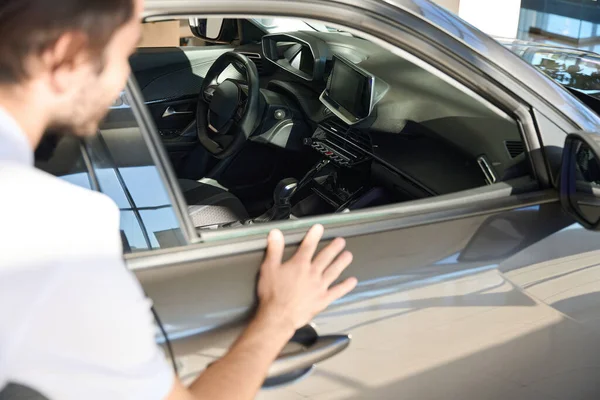 Cropped photo of auto dealership client looking inside automobile through open window