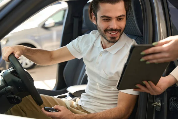 Χαμογελώντας Νεαρός Άνδρας Κάθεται Μηχανοκίνητο Όχημα Ενώ Διαβάζετε Ψηφιακό Έγγραφο — Φωτογραφία Αρχείου