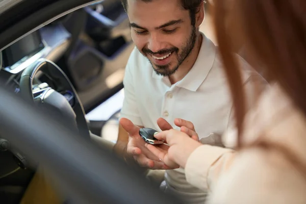 幸せな若い自動車販売のディーラーの顧客は販売コンサルタントからの自動車キーのFobを得る — ストック写真
