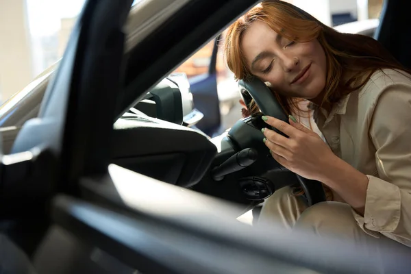 Serene female driver lying with eyes closed on steering wheel of automobile