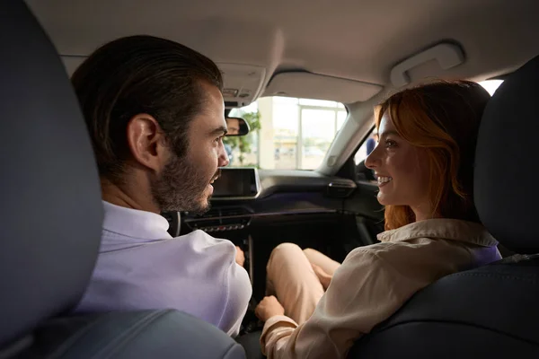 Smiling happy young woman sitting beside pleased young man in luxury car
