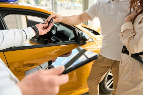 Cropped photo of Caucasian couple getting car key fob from sales consultant