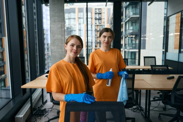 Two pretty young women in work clothes and blue gloves in a coworking space