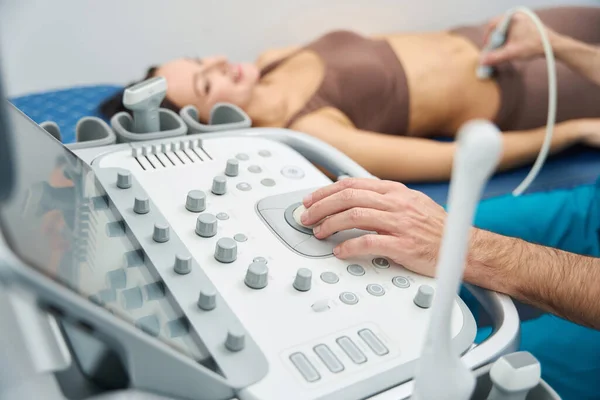 stock image Relaxed patient lies on a medical couch while the doctor inserts a probe on the right side of the abdomen