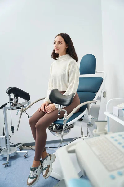 Przemyślana Pacjentka Badająca Stan Zdrowia Siedząc Krawędzi Krzesła Manipulacji Medycznej — Zdjęcie stockowe