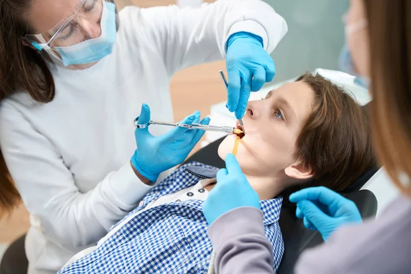 儿童在拔牙前注射麻醉药物 医生和一名身着制服和手套的助手 — 图库照片