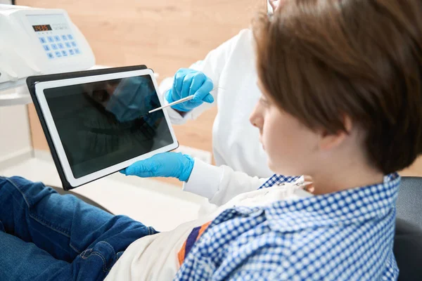 Dentista Consultando Paciente Jovem Consultório Odontológico Médico Usa Tablet Localizador — Fotografia de Stock
