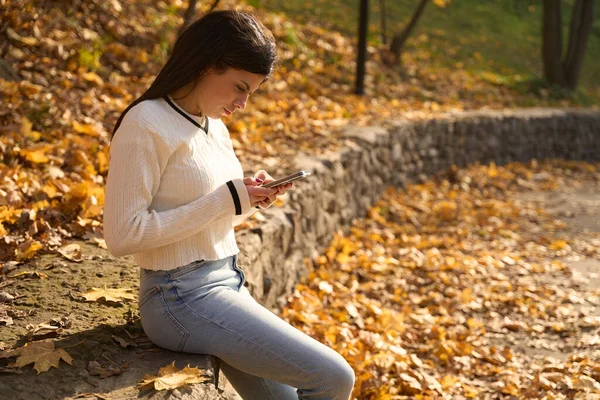 Rosnąca Młoda Kobieta Trzyma Telefon Rękach Siedzi Parapecie Parku — Zdjęcie stockowe