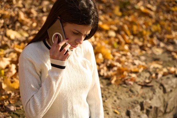 耳の近くに携帯電話を持っている若い女性を動揺させ 背景に黄色の葉 — ストック写真