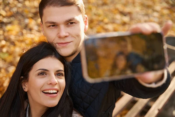 Piękna Młoda Para Robi Sobie Selfie Jesiennym Parku Szczęśliwi Uśmiechnięci — Zdjęcie stockowe