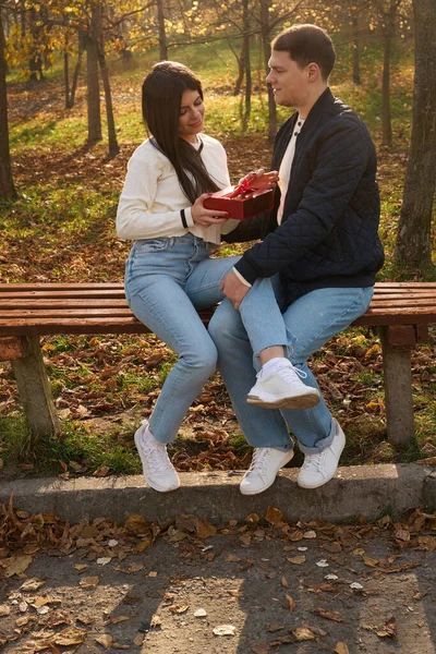 Egy Fiatal Ajándékdobozt Tart Masnival Kezében Barátja Padon Ülnek Parkban — Stock Fotó