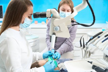 Modern diş kliniğinde diş kanallarının tedavisi mikroskop altında gerçekleştirilir, dişçi bir asistanla çalışır