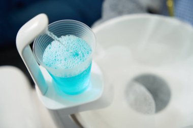 Modern bir diş muayenehanesinde bir hastanın ağzını çalkalamak için özel bir dezenfektan çözeltisi olan cam.