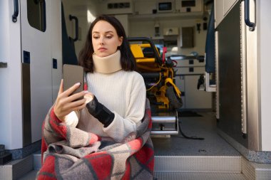 Sabitlenmiş boynu olan üzgün hasta cihaz ekranına bastırırken elini göz hizasına kaldırdı.