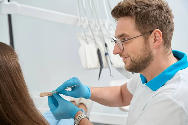 上颌骨模型门牙处用医疗器械向患者微笑的牙科保健员 — 图库照片