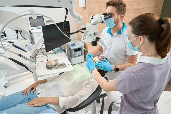 有经验的牙医在女护士的协助下摘除病人中央门牙间的牙垢 — 图库照片