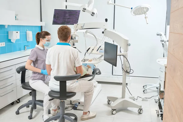 Pohled Zezadu Stomatologa Ošetřujícího Klientovy Zuby Pod Mikroskopem Asistence Ošetřovatelky — Stock fotografie