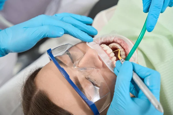 看護師が補助する女性患者の歯間の歯間微積分を除去する経験豊富な医師 — ストック写真