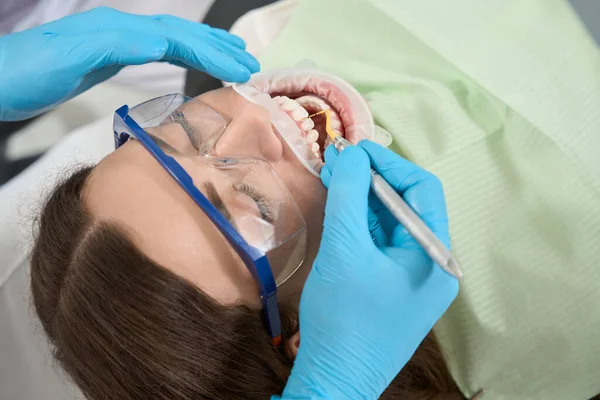 女性患者の上顎中央切開部の間のタールを除去するニトリル手袋の歯科手 — ストック写真