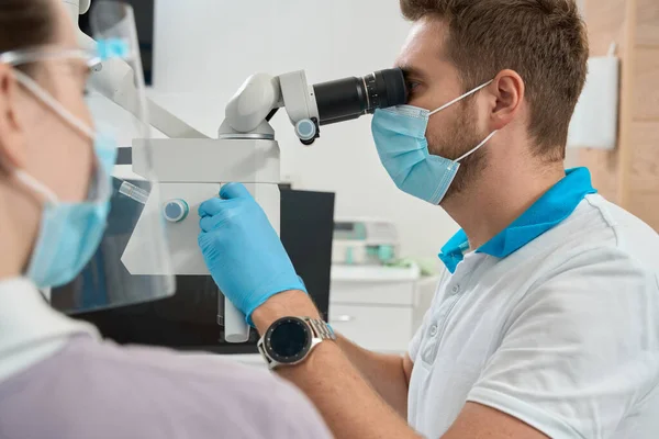 Стоматолог Дивиться Через Окуляри Мікроскопа Повертає Ручку Фокуса Під Керівництвом — стокове фото