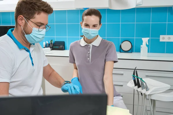 认真专注的女护士看着电脑显示器 而口腔科医生则对病人进行牙科治疗 — 图库照片