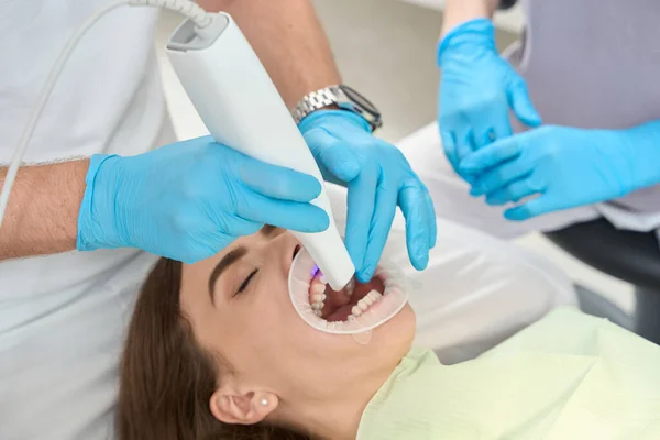 助手によって監督される女性患者の上顎前歯にデジタル口腔内スキャナを指示歯科医師 — ストック写真