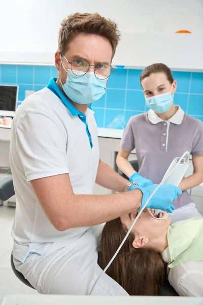 深刻な歯科医は 女性看護師によって支援若い女性の口内スキャンを実施 — ストック写真