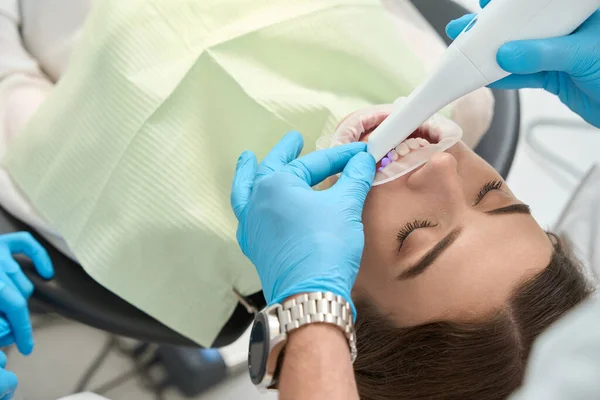 使い捨てニトリル手袋の歯科医の手のクローズアップ診断装置で患者の前歯をスキャン — ストック写真