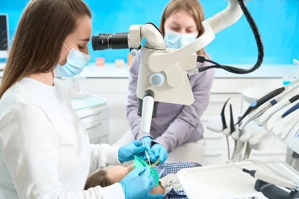 stock image Treatment of dental canals in modern dental clinic is carried out under a microscope, the dentist works with an assistant