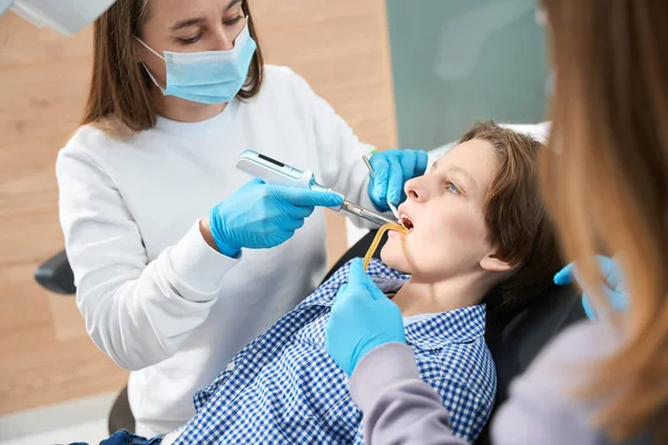 職場の女性歯科医は特別なツールで働いています アシスタントは彼女を助けます — ストック写真
