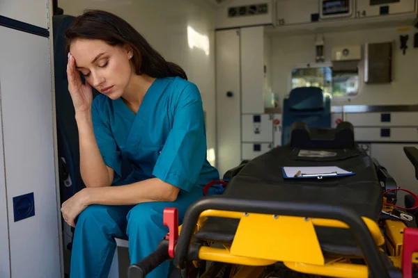 車の緊急時の部屋のストレッチャーの横の席で彼女の目を閉じた看護師の気分 — ストック写真
