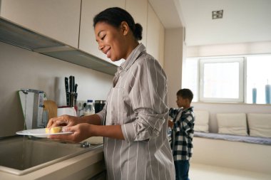 Mutfakta bulaşıkları yıkayan mutlu, pozitif Afrikalı bir kadının belden yukarısı portresi.