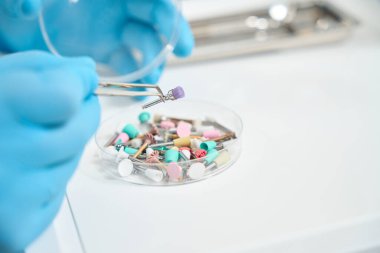 Naylon kıllı diş fırçası tutan azot eldivenli dişçi ellerinin kesilmiş fotoğrafı.