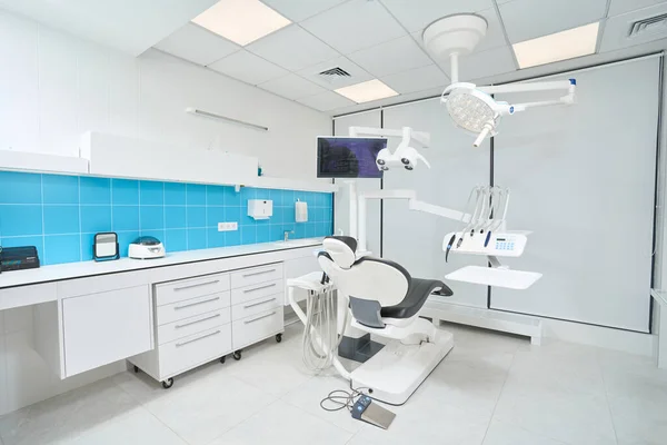 stock image Spacious dentist office with empty leather dental chair and bright overhead lighting