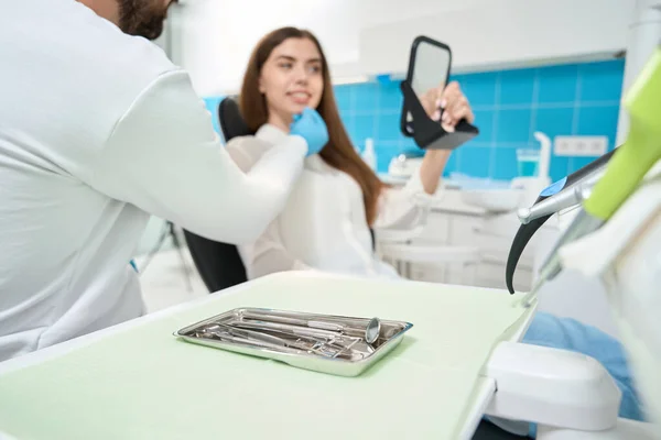 Paciente Mirando Sus Dientes Espejo Mano Mientras Escucha Estomatólogo Durante —  Fotos de Stock