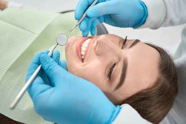 歯医者でニトリル手袋保持口ミラーと歯のプローブ上笑顔患者の顔 — ストック写真