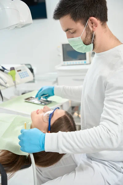 Dentista Mirando Paciente Tranquilo Tumbado Una Silla Dental Mientras Elige —  Fotos de Stock