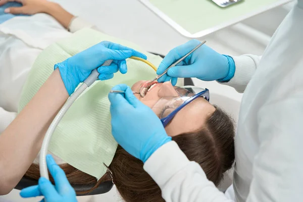 歯科探検家と口鏡を使用して女性のクライアントの歯と歯茎を調べるニトリル手袋の医師 — ストック写真