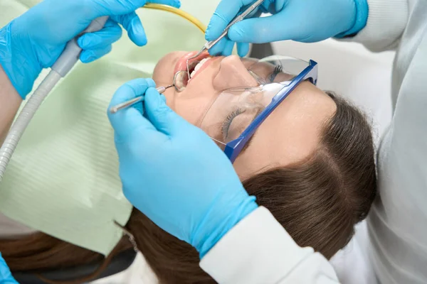 有经验的口腔学家 戴着硝酸盐手套 用牙科探头和口镜检查妇女口腔 — 图库照片