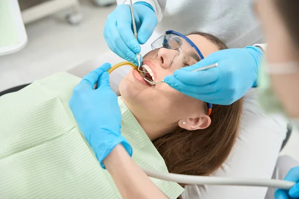 看護師の補助を受けた診断ツールを用いて女性患者歯の一次検査を行う歯科医師 — ストック写真