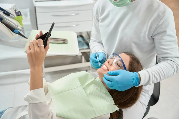 医生检查前牙时照镜子的女病人 — 图库照片