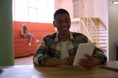 Arka planda oturan bayanla tablet kullanan mutlu Afrikalı Amerikalı adam.