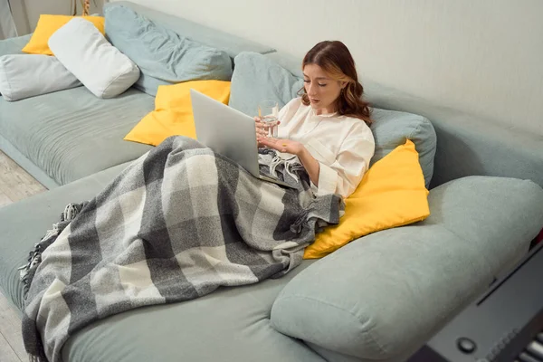 Θηλυκό Κάθεται Στο Κρεβάτι Φορητό Υπολογιστή Κρατώντας Ένα Ποτήρι Νερό — Φωτογραφία Αρχείου