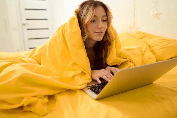 Calm Focused Woman Lying Bed Wrapped Blanket Typing Portable Computer — Foto Stock