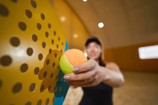 アスレチック女性は 屋内プレイエリアにいる間 ラケットの横にテニスボールを手に持っています — ストック写真
