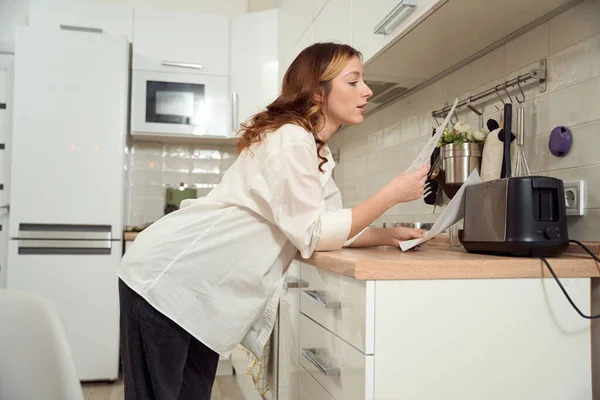 Calm Concentrated Female Looking Documents Her Hands While Leaning Kitchen — Fotografia de Stock