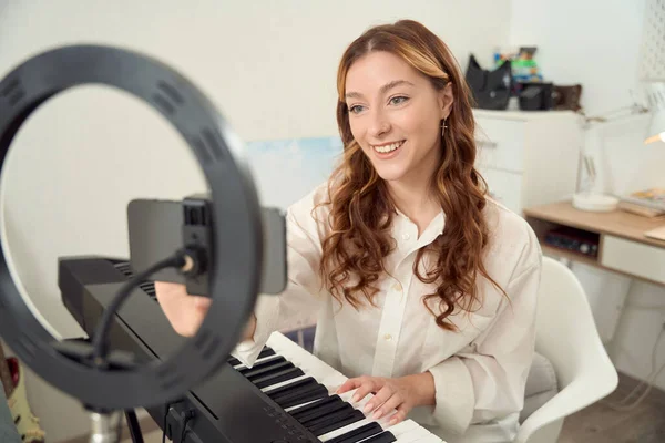 Smiling Pleased Female Musician Seated Synthesizer Adjusting Settings Smartphone — Foto Stock