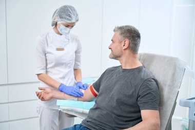 Smiling patient takes a blood test from a vein, a health worker fixes a patch on a man arm