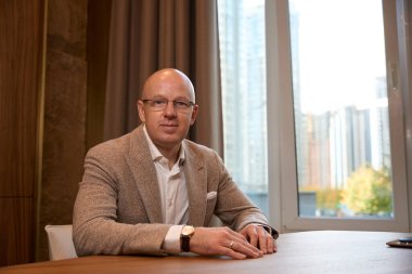 Successful handsome man in a business suit sits in the office at the view window